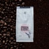 Bag of ground coffee surrounded by coffee beans
