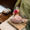 Elderly woman wearing a pink flower corsage and holding a woven clutch