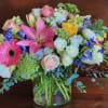 Mixed bouquet of pink, white, yellow, and blue flowers in a glass vase