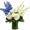 White roses and hydrangeas with blue and green orchids in a glass vase