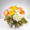 Bouquet of yellow, peach, and white roses in a clear glass vase
