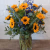 Sunflowers and blue flowers in a clear glass vase