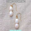 Pair of pearl drop earrings with gold hooks on a fabric background