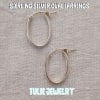 Pair of silver oval hoop earrings on a textured fabric background