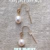 Pair of pearl drop earrings on a textured fabric background