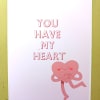 White greeting card with pink text 'You Have My Heart' and a smiling pink heart character hugging itself.