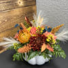 White ceramic pumpkin container with a mix of dried and live florals.
