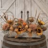 Autumn floral arrangement in a rectangular glass vase with pumpkins and sunflowers