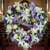 Heart-shaped floral wreath with white lilies, roses, and purple blooms