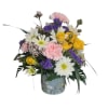 Mixed bouquet of yellow roses, white daisies, pink carnations, and purple filler in a floral vase