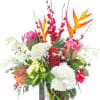 Tropical bouquet with pink protea, white hydrangeas, and red berries in a glass vase