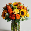 Bouquet of sunflowers and orange roses in a clear glass vase