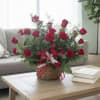 Basket arrangement of red roses with ribbon on a coffee table