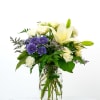 White lilies and purple daisies in a glass jar vase