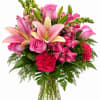 Pink lilies, roses, and carnations in a clear glass vase