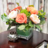 Coral and white roses arranged in a square glass vase