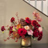 Mixed red and pink flower arrangement in a gold vase