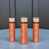 Three orange Honey Hill Farm lip balm tubes standing on a round light blue surface