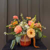 Peach and coral mixed flower arrangement in a two-tone vase