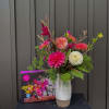 Bright pink and white dahlia bouquet in a white vase beside a dahlia puzzle box