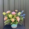 Pastel mixed flower arrangement in a blue ceramic vase