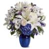 White lilies and daisies with purple accents in a blue vase