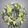 Large floral wreath with white roses, blue hydrangeas, and green blooms