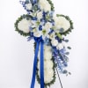 Standing floral cross with white blooms, blue flowers, and a blue ribbon