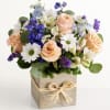 Bouquet of peach roses, white daisies, and blue flowers in a wooden box