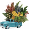 Yellow and green mixed flowers arranged in a turquoise ceramic truck-shaped container