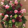 Large pink and burgundy floral arrangement in a wicker stand