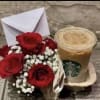 Small bouquet of red roses with baby's breath beside an iced Starbucks drink