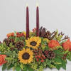 Autumn floral centerpiece with sunflowers, roses, pinecones, and two burgundy candles