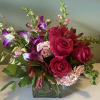 Pink roses and purple orchids arranged in a square glass vase