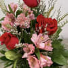Bouquet of red roses and pink flowers in a clear glass vase