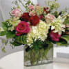 Mixed roses and white blooms in a square glass vase