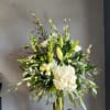 Tall white floral arrangement in a clear glass vase with lilies and hydrangea