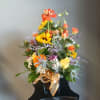 Mixed bouquet in a black vase with orange, yellow, and purple flowers