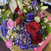 Mixed bouquet with red and pink roses, purple blooms, and green buds
