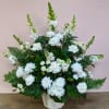 White floral arrangement in a textured white vase with fern accents