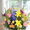 Sunlit yellow lilies and sky-blue delphinium rise above a lush mix of