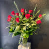 Red roses arranged in a clear glass vase with eucalyptus foliage