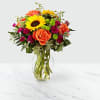 Bouquet of orange roses and yellow sunflowers in a clear glass vase
