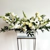 White floral arrangement in a rectangular vase with long greenery