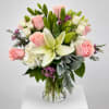 Pink roses and white lilies arranged in a clear glass vase