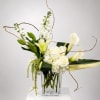 White roses, calla lilies, and orchids in a clear glass vase