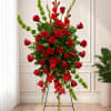 Tall standing arrangement of red roses and red flowers with green accents
