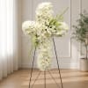 White floral cross arrangement on a stand with lilies and roses