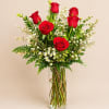 Red roses and white filler flowers in a clear glass vase