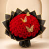 Large bouquet of red roses wrapped in black paper with gold trim and butterfly accents